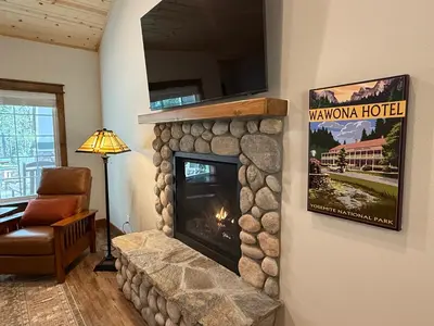 a living room with a fireplace with a tv above it at Black Bear Bungalow in White Wolf