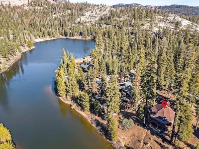 an aerial view of a lake with a house and trees at The Lake Chalet in Bear Valley
