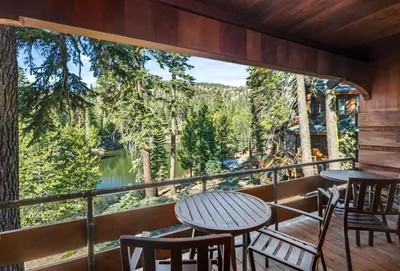 a balcony with tables and chairs and a large window at The Lake Chalet in Bear Valley