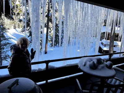 a person standing in front of a window in the snow at The Lake Chalet in Bear Valley