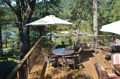 a deck with a table and chairs and an umbrella at Lakeside Cabin with lake view in Bass Lake