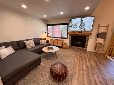 a living room with a couch and a flat screen tv at Cozy Mtn Condo - Hot Tub - Walk to Canyon Lodge in Mammoth Lakes