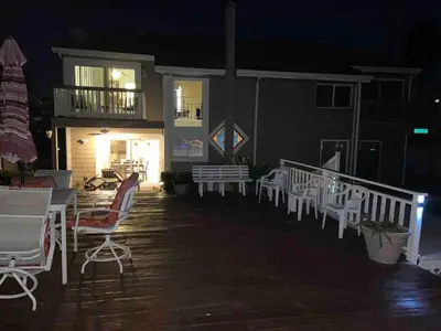 a group of chairs and tables on a deck at night at Waterfront Sleeps 6 near Marina with Hot Tub in Discovery Bay