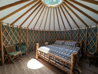 a bedroom in a yurt with a bed and a chair at Big Woods Retreat in Miramonte