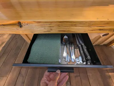 a person holding a drawer in a table with utensils at Big Woods Retreat in Miramonte
