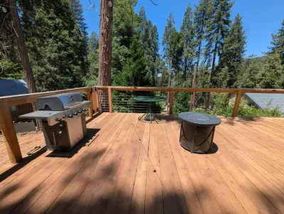 a patio with a grill and a table on a deck at Big Woods Retreat in Miramonte