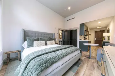 a bedroom with a large bed and a kitchen at Catamount Lodge 101B by East West Hospitality in Truckee