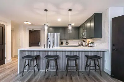 a kitchen with green cabinets and bar stools at Catamount Lodge 101B by East West Hospitality in Truckee