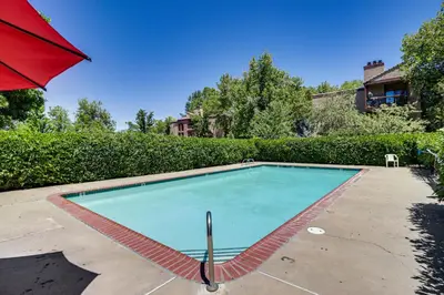 a swimming pool with a red umbrella in a yard at Walk to Virginia Lake Reno Condo with Balcony! in Reno