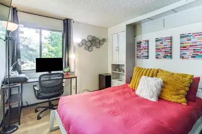 a bedroom with a red bed and a desk with a computer at Walk to Virginia Lake Reno Condo with Balcony! in Reno