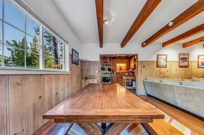 a dining room with a wooden table and a kitchen at Tahoe City Gem Pet Friendly Yard Walk to Beach in Tahoe City