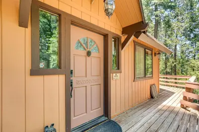 a door to a house with a cat sitting on the porch at Cabin Getaway Near Big Trees Park Game Room, Deck in Camp Connell