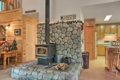 a living room with a stone wall with a stove at Game Room and Deck Pet-Friendly Camp Connell Cabin in Camp Connell