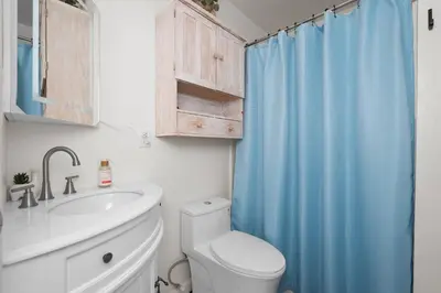 a bathroom with a toilet and a blue shower curtain at Yosemite+5BR+Views+Hot Tub+Pets in Coarsegold