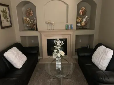 a living room with two black couches and a fireplace at Furnished five bedroom and gated community in Patterson