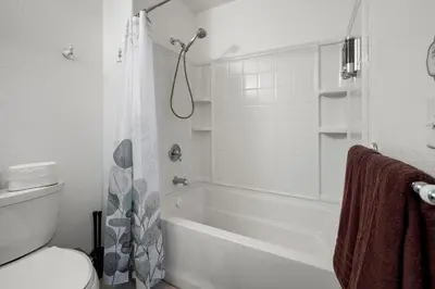a white bathroom with a tub and a toilet at Yosemite-bound, Fun at the lake, Spacious & stylish 6 Bdr home with game room in Groveland