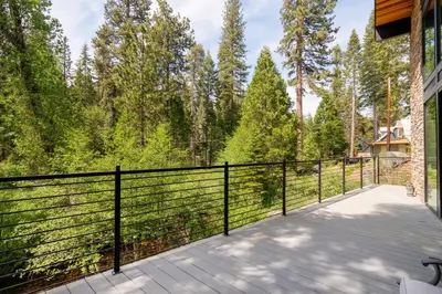 a balcony with a black fence and trees at Mariposa Grove Creekside Retreat - To be featured on STAYCATION on the Destination Channel in 2026! in Fish Camp