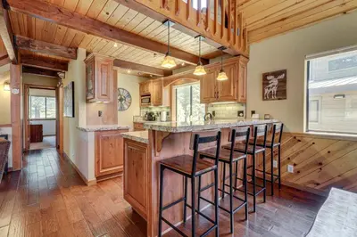 a kitchen with wooden cabinets and a bar with stools at 1 Mi to Tahoe Donner Skiing Luxe Truckee Cabin! in Truckee