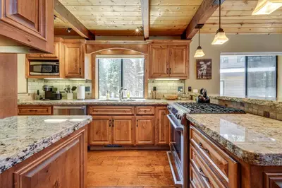 a large kitchen with wooden cabinets and granite counter tops at 1 Mi to Tahoe Donner Skiing Luxe Truckee Cabin! in Truckee