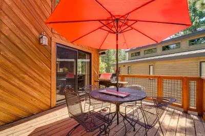 a table and chairs with an umbrella on a deck at 1 Mi to Tahoe Donner Skiing Luxe Truckee Cabin! in Truckee
