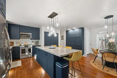 a kitchen with blue cabinets and a kitchen island with chairs at Midtown Bungalow in Reno