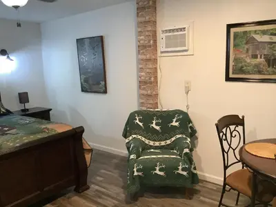 a bedroom with a bed and a chair and a table at Shady Creekside Cabin in Miramonte
