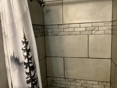 a bathroom with a shower with a shower curtain at Shady Creekside Cabin in Miramonte