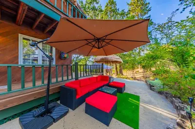 a patio with a red couch and an umbrella at Vintage Sunset Villa by Bass Lake 17 miles from Yosemite National Park in Oakhurst
