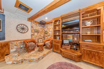 a living room with a stone wall at Vintage Sunset Villa by Bass Lake 17 miles from Yosemite National Park in Oakhurst