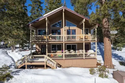 a house with a wrap around deck in the snow at Catalpa Vista By Hauserman Rentals in Tahoe Vista