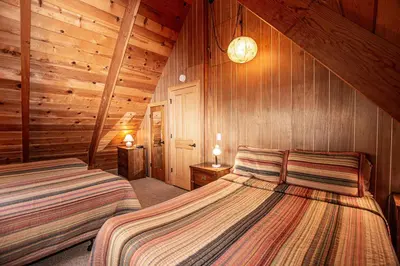 two beds in a room with wood paneled walls at Das Berghaus By Hauserman Rentals in Tahoe City
