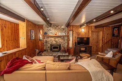 a living room with a couch and a stone fireplace at Edelweiss Escape By Hauserman Rentals in Tahoe City
