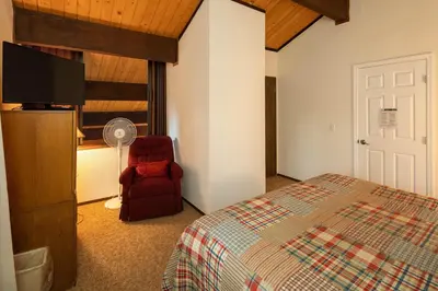 a bedroom with a bed and a chair and a flat screen tv at Grainger By Hauserman Rentals in Tahoe City