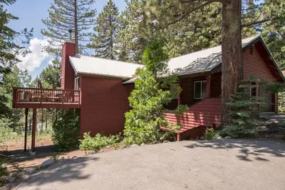 a red house with a deck in the woods at Highlands Lodge By Hauserman Rentals in Tahoe City