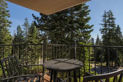 a table and chairs on a balcony with trees at Carnelian Woods #126 By Hauserman Rentals in Carnelian Bay