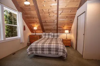 a bedroom with a bed and wooden ceilings and a window at Hillhouse By Hauserman Rentals in Homewood