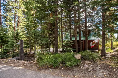 a cabin in the woods with a fence and trees at Little Bear Cabin By Hauserman Rentals in Tahoe Vista