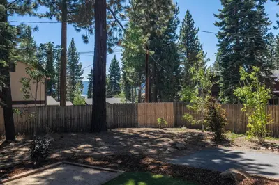 a backyard with a wooden fence and trees at Cedarwood Serenity By Hauserman Rentals in Tahoe City