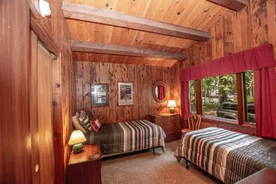 a bedroom with two beds in a room with wooden walls at Plesums By Hauserman Rentals
