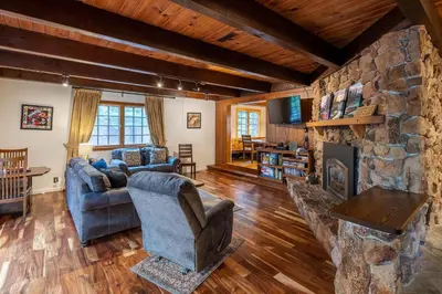 a living room with a stone fireplace and a blue couch at Molly's Treehouse By Hauserman Rentals in Carnelian Bay