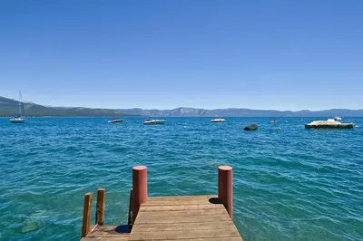 a wooden dock in the middle of a large body of water at Rygh Lakefront By Hauserman Rentals in Carnelian Bay
