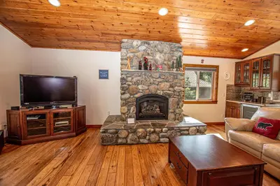 a living room with a stone fireplace and a tv at Tahoe Haven By Hauserman Rentals in Carnelian Bay