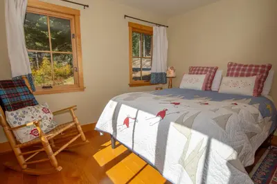 a bedroom with a bed and a chair and windows at Snowglobe By Hauserman Rentals in Tahoe City