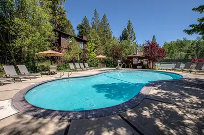 a swimming pool with chairs and an umbrella at St Francis #14 By Hauserman Rentals in Tahoe City