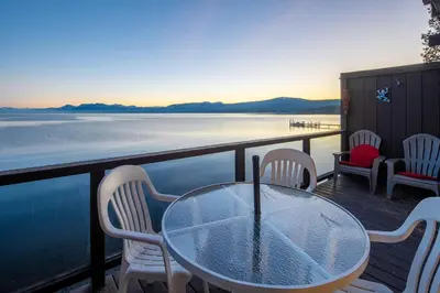 a table and chairs on a deck with a view of the water at Star Harbor # 15 By Hauserman Rentals in Tahoe City