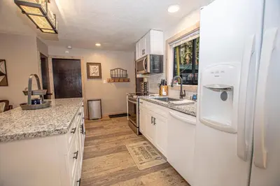 a kitchen with white cabinets and a sink and a refrigerator at Tahoma Treasures Emerald Cabin Hauserman Rentals in Tahoma