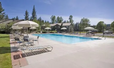 a swimming pool with lounge chairs and umbrellas at Lake Forest Glen # 114 By Hauserman Rentals in Tahoe City