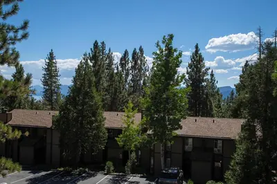 an apartment building with a parking lot and trees at Dollar Hill II # 25 By Hauserman Rentals in Tahoe City