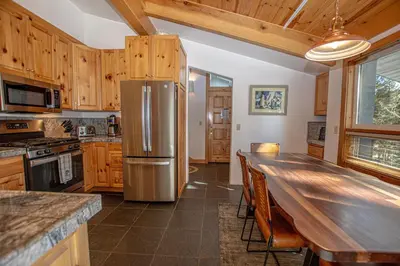a kitchen with a refrigerator and a long table at KT22 View By Hauserman Rentals in Olympic Valley