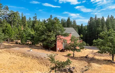 an aerial view of a red house in the woods at Prasad Retreat - Sunny Home with Deck & Air Hockey home in Arnold